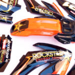 pitbike černé plasty CRF70 s polepy Rockstar/oranžové Stomp, DemonX, WPB